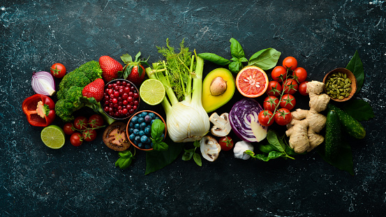 Food. Set of fresh vegetables and fruits on a black stone background. Organic food. Top view. Free space for your text.