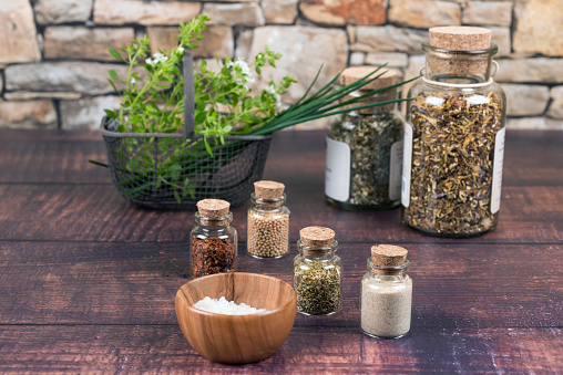 Spices in small bottles, salt, basil and chives on a wooden table