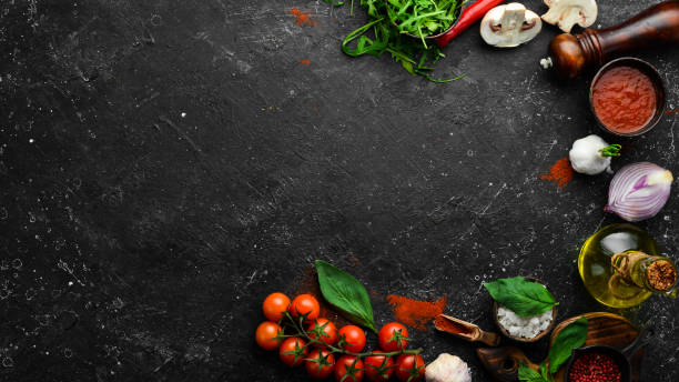 istock Kitchen cooking background: cherry tomatoes, onions, spices and herbs. On a black background. 1347070113