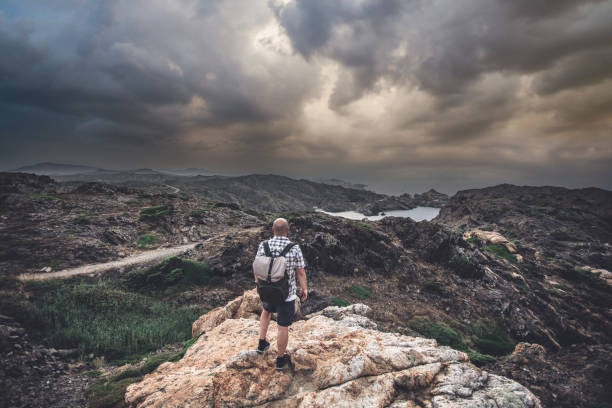 Dramatic sky above rocky landscape and a man with backpack