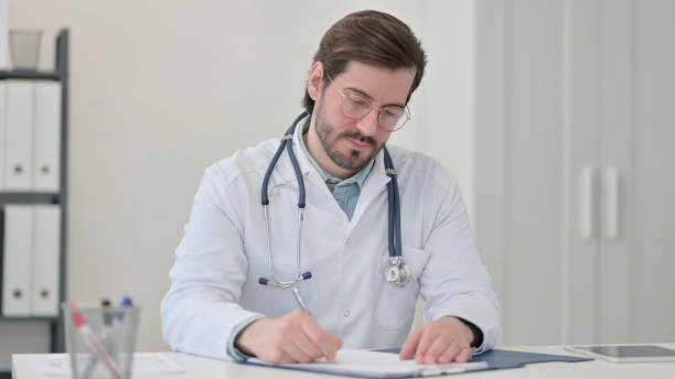istock Young Doctor Writing on Paper at Work 1347075963