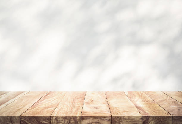 istock White wood table top with shadow of tree leaf on wall background. 1347076086