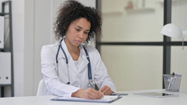 istock Female African Doctor Writing on Paper 1347078579