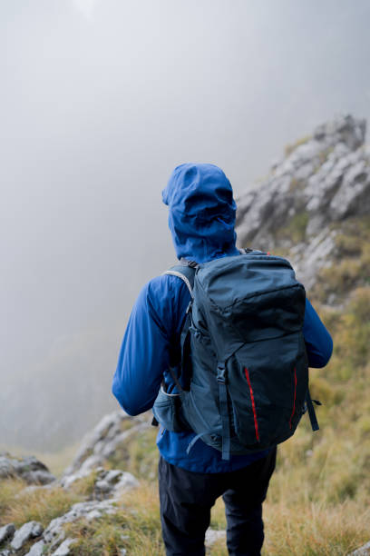 istock Man hikes along mountain ridge through dense fog 1347078873