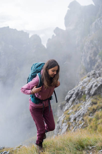 istock Young woman hikes up grassy mountain ridge 1347078926