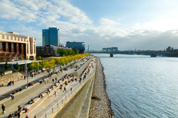 Cologne, Germany - October 16, 2021. Many tourists and locals enjoy the last rays of sunshine on the steps of the Rhine boulevard in the pandemic summer of 2021