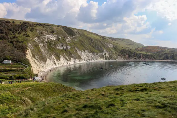 View of the Lulworth Cove from above and with grass fields on a sunny day
