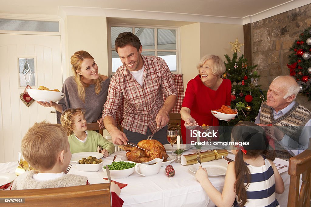Family serving Christmas dinner Three Generation Family serving Christmas dinner smiling and laughing at each other Christmas Stock Photo