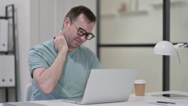 istock Young Man having Neck Pain while working on Laptop 1347080493