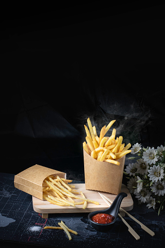 French fries fried yellow on a black background with smoke