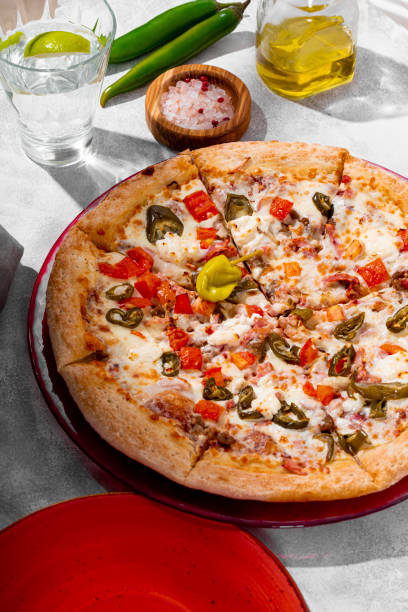 istock Spicy pizza with chicken, tomatoes and jalapenos on the light gray table vertical photo 1347081440