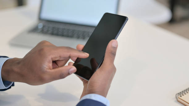 istock Hands of African Businessman using Smartphone, Close up 1347081495