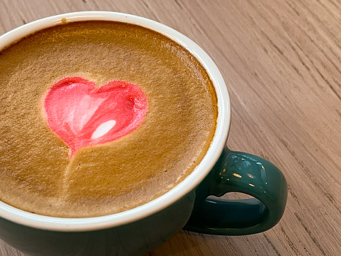 Cup of coffee latte with heart shape and coffee beans on old wooden background