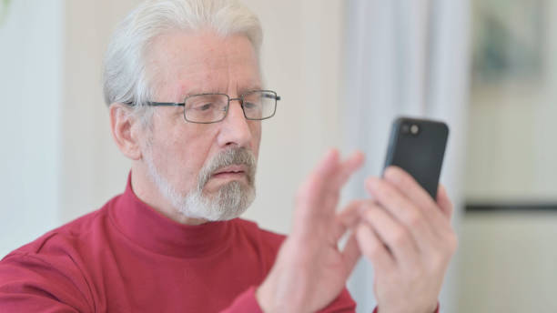 istock Close up of Old Man Browsing Internet on Smartphone 1347081990