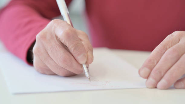 istock Hands of Old Man Writing on Paper 1347083187