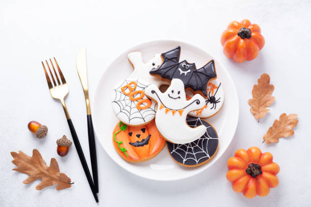 istock Halloween table setting with gingerbread cookies on white plate and cuterly on white background. Bright homemade cookies for Halloween party 1347083472