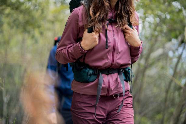 pareja de excursionistas sigue el sendero a través de un exuberante bosque - beautiful red pink wood fotografías e imágenes de stock