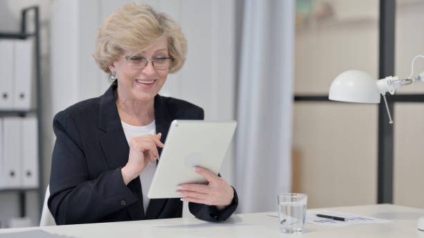 istock Old Businesswoman Talking on Video Chat on Tablet 1347086880
