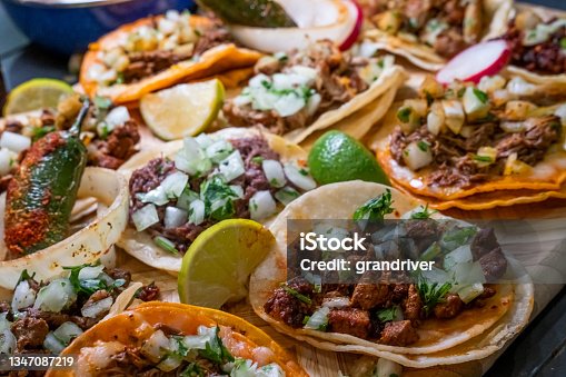 istock Assortment Of Delicious Authentic Tacos, Birria, Carne Asada, Adobada, Cabeza And Chicharone, Arranged With Lime Slices, Onion, And Roasted Chili Pepper 1347087219