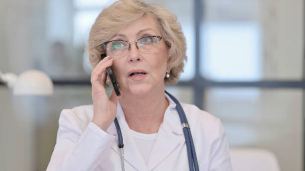 old female doctor talking on phone - nurse on phone serious bildbanksfoton och bilder