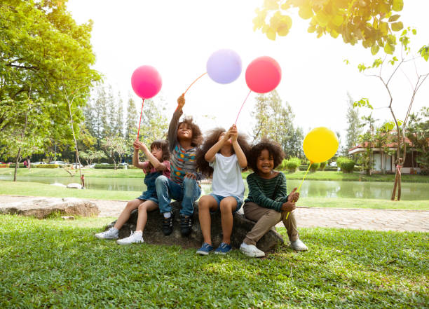 多様な子供たちのグループは、公園でカラフルな風船を演奏しています。 - playground cute baby blue ストックフォトと画像