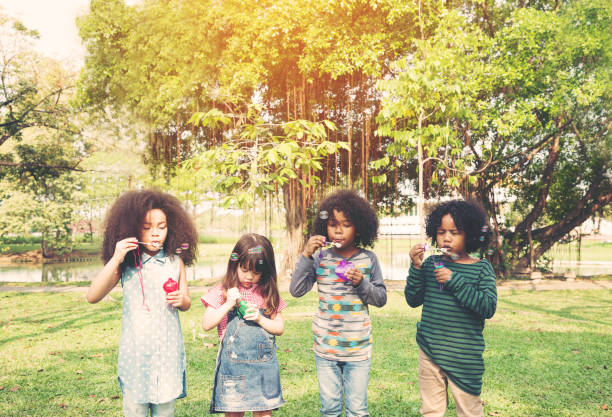 istock Group of children playing blowing bubbles fun 1347088924
