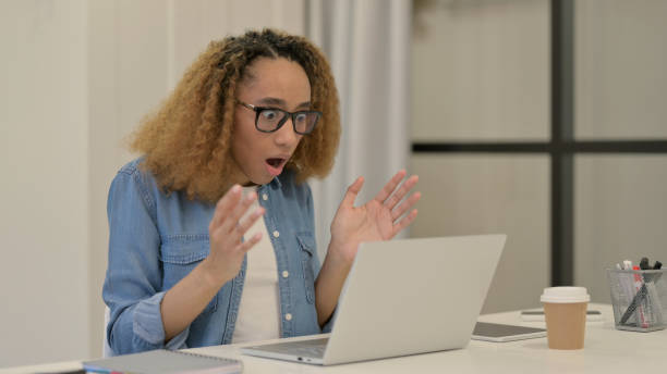 istock Beautiful African Woman Reacting to Loss While using Laptop 1347091335