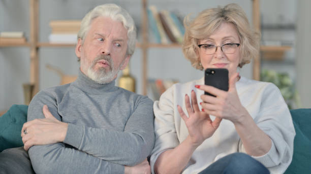 istock Old Woman Busy with Smartphone While Old Man is Sitting Annoyed 1347091640
