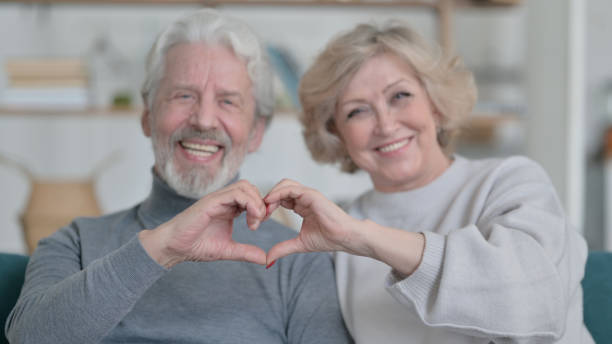 istock Old Couple Holding Hands Together in Heart Shape 1347091823
