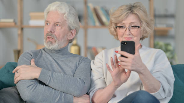 istock Old Woman Busy with Smartphone While Annoyed Old Man Sitting Aside 1347092968