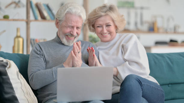 istock Old Couple Celebrating Success while using Laptop at Home 1347093110