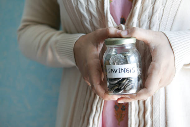 istock women hand hold a saving coins jar 1347093188
