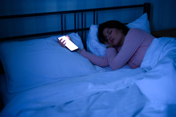 istock Woman sleeping in her bed while her smartphone is still on 1347095763