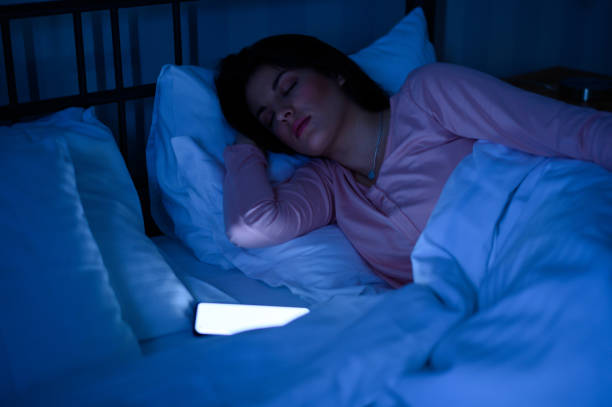 istock Woman sleeping in her bed while her smartphone is still on 1347095767