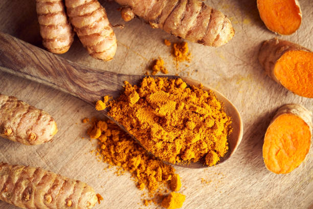 istock Curcuma powder on a spoon with fresh whole and cut up turmeric root 1347099131