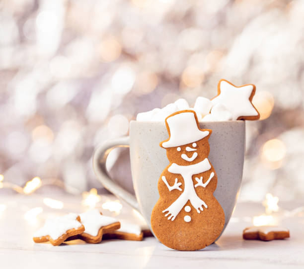 Cute Gingerbread Snowman Cookie in front of Hot cocoa with Marshmallows.