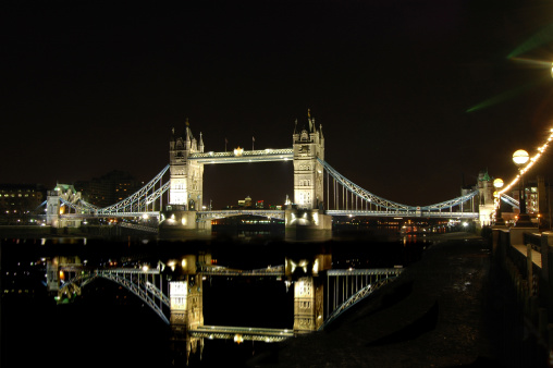 London Tower Bridge by night. Long exposure picture with the bridge reflected in the water.