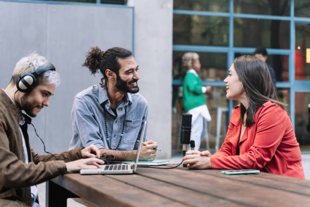 istock Young journalist content creator recording informal conversation interview with trendy woman. Modern millennial people making podcast for online social media radio networks. Focus on bearded man 1347100930