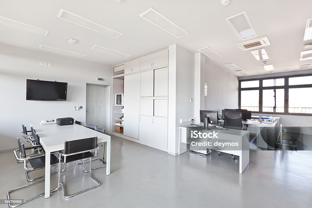 Modern office with white furniture, cupboard and conference desk Modern office with white furniture, cupboard, conference desk and walls and with plasma TV on the wall Board Room Stock Photo