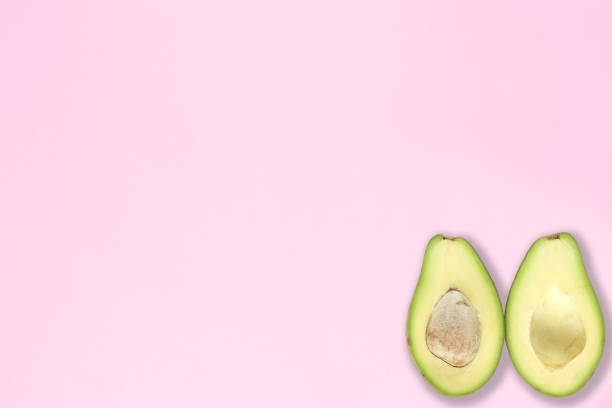 istock Two halfs of avocado with and without seed on pink background. Top view. 1347102126