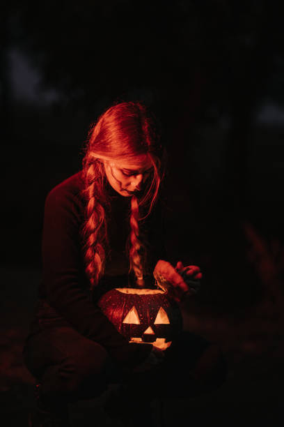 eine junge frau mit bühnen-make-up für halloween mit gebogenem kürbis - braids men black evil stock-fotos und bilder