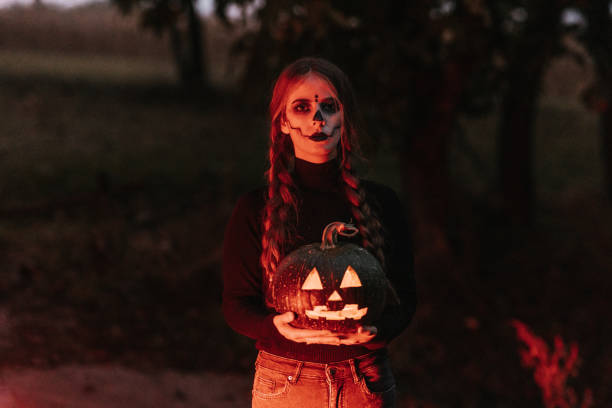 młoda kobieta z makijażem scenicznym trzymająca rzeźbioną dynię na halloween - braids men black evil zdjęcia i obrazy z banku zdjęć