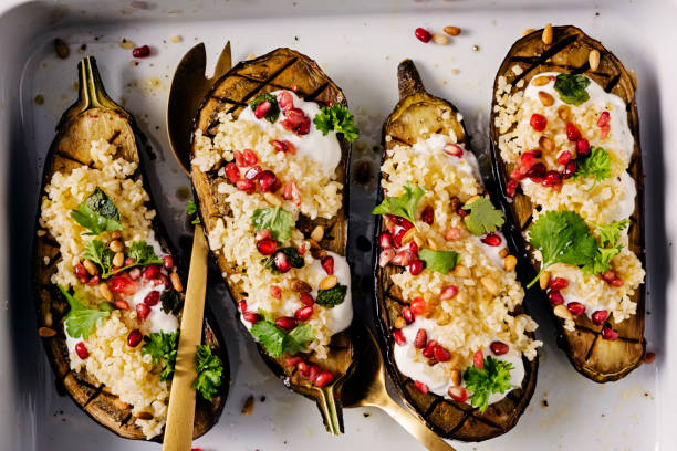 Roasted Aubergine with Bulgar and Pomegranate Vegetarian dish of roasted aubergine with bulgar, pomegranate, mint and parsley, perfect for lunch or a light dinner. The aubergines are cut in half and the flesh is cut in a checkerboard style and brushed with olive oil and baked for around 30 mins. The bulgar is made according to the packet instructions and garlic, lemon juice and olive oil are added for flavour. A yoghurt dressing is poured onto the baked aubergine and the bulgar and pomegranate seeds are are placed on top finished off with some fresh parsley and mint. Colour, horizontal format with some copy space. bulgur wheat stock pictures, royalty-free photos & images