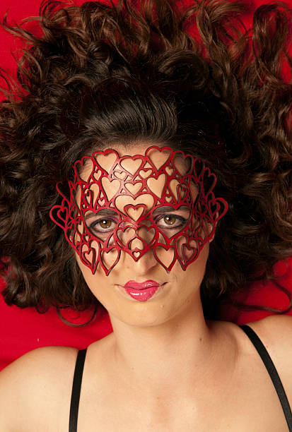 Young, beautiful Caucasian woman wearing red mask of hearts stock photo