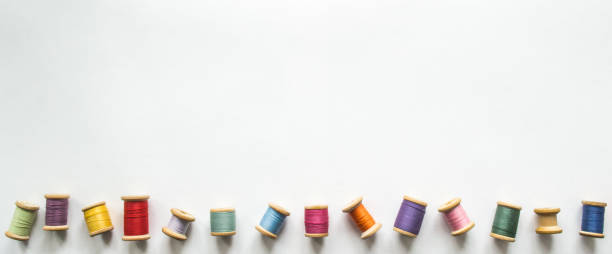 ots of multicolored threads on old-fashioned wooden reels on a white background with space for text. One of the thread reels is empty