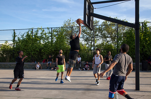 Bronx, New York, USA - June 9, 2019: African American men play basketball in park.