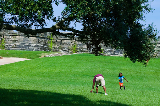 Landscape. Father and son play football in the field in front of the fort. Created in St. Augustine, FL, Aug 8, 2021.
