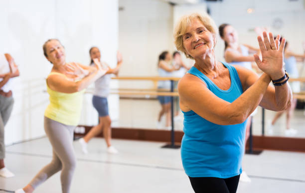 Portrait of an mature European woman enjoying energetic dancing in the studio Portrait of an active mature European woman enjoying modern energetic dancing in a female group in the studio active seniors stock pictures, royalty-free photos & images