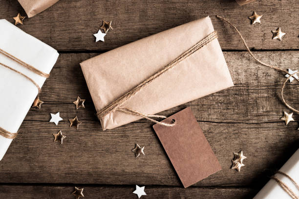 istock Gift box in kraft paper with a large tag for copy space on a dark background top view. Rustic greeting card mockup with aged wood. 1347118916