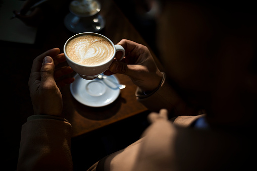 Closeup shot of an unrecognizable man having a cup of coffee at a cafe